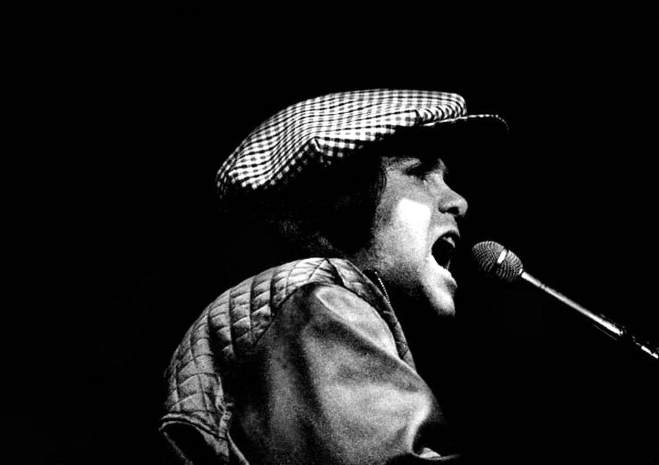 Elton John singing at the piano in concert, late 1970s