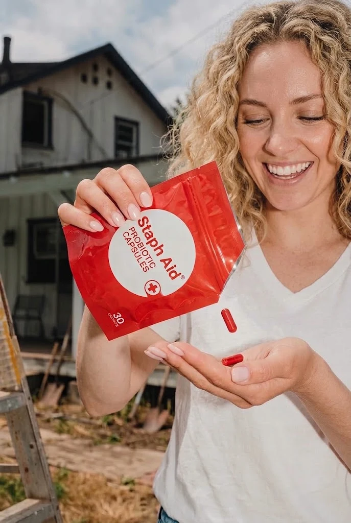 Woman pouring a Staph Aid capsule from the pouch into her palm